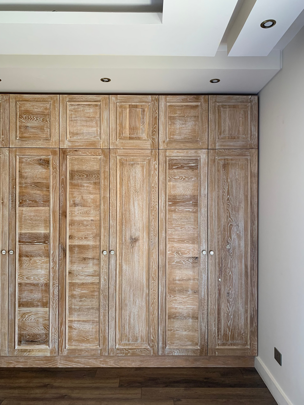 Wooden wardrobe with a rustic finish in a room with white walls and a white ceiling.